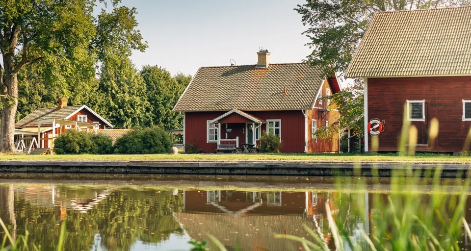 A couple of red houses sitting next to a body of water.
