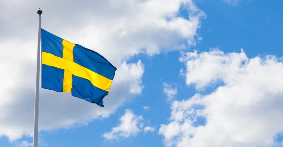 Svenska flaggan mot himmel med moln