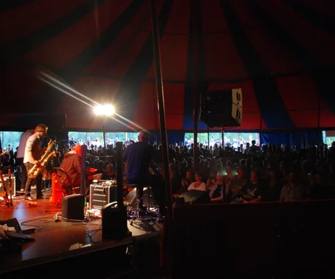 En grupp människor som sitter runt en scen där en person spelar gitarr.