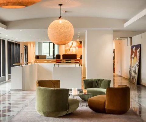 En bild på en hotellobby med schackrutigt golv, vita väggar och gröna och senapsgula fåtöljer.