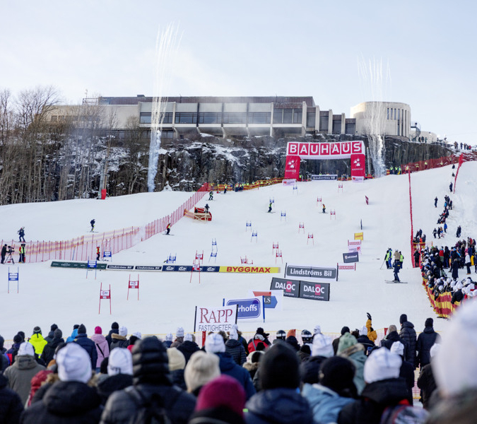 En folkmassa som står på toppen av en snötäckt sluttning.