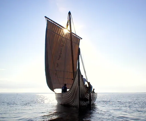 Ett vikingaskepp i kvällssolen på öppet vatten.