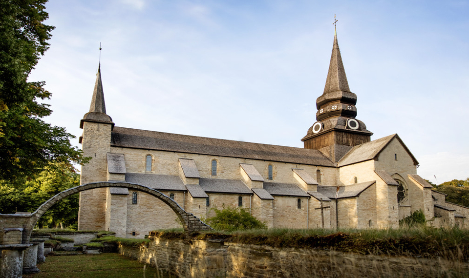 En gammal kyrka med ett stenvalv framför sig.