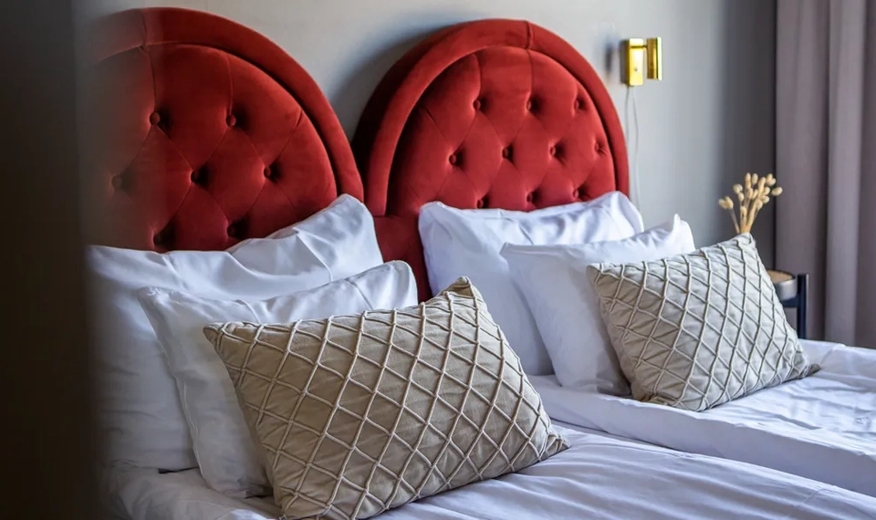 En skön hotellsäng med röd sänggavel