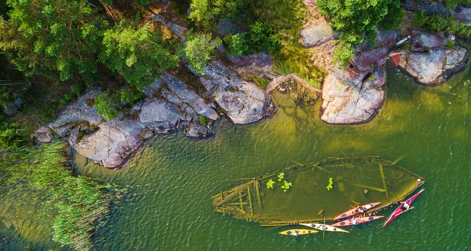 Ett vrak som ligger nära land i vattnet. Det syns ovanifrån.