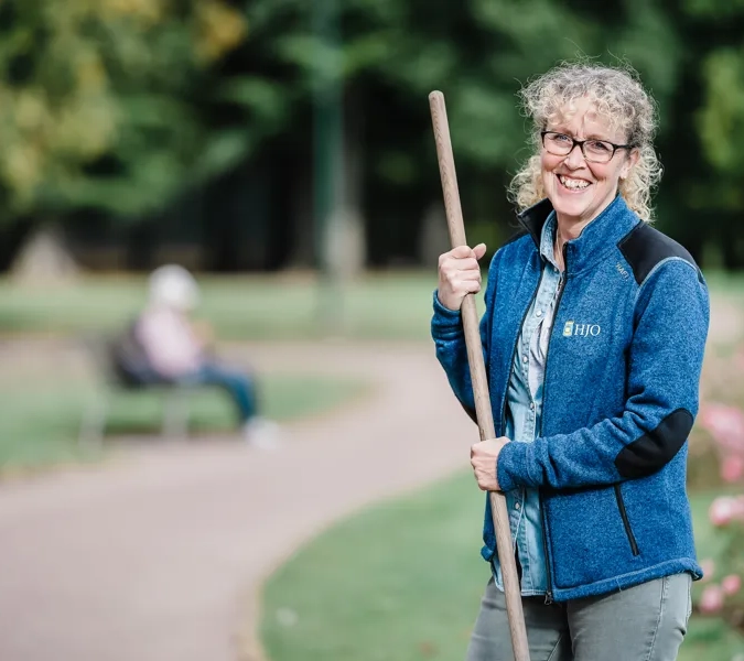 En kvinna håller i en pinne i en park.