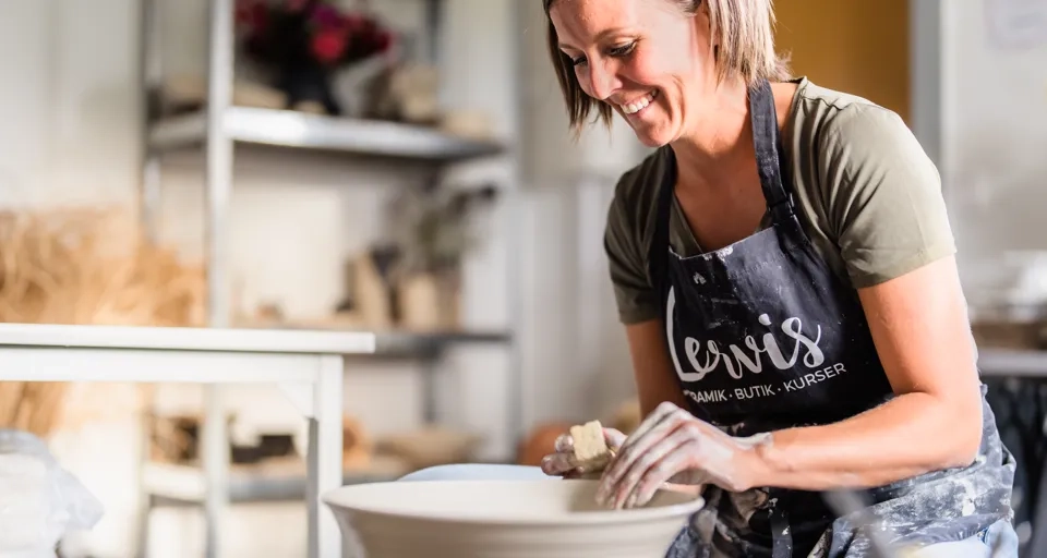 En kvinna i förkläde gör en skål.