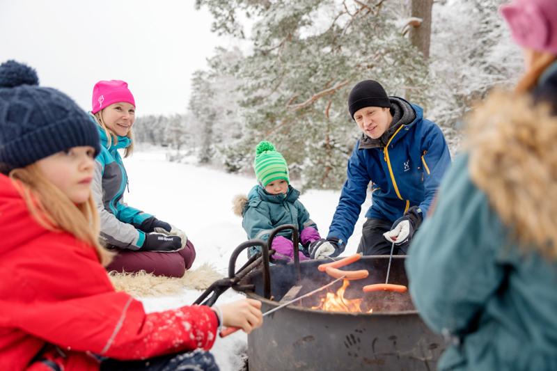En grupp människor som sitter runt en eld i snön.