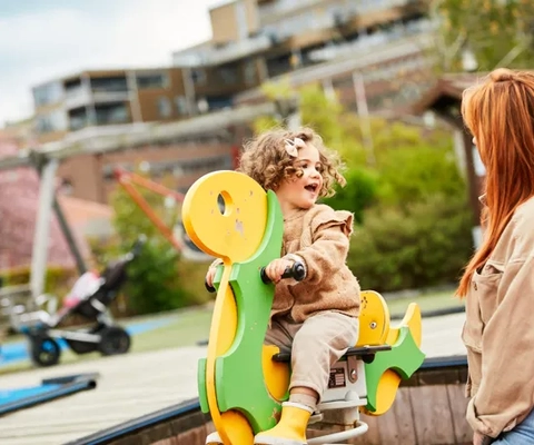 En kvinna och ett barn leker på en leksaksbåt.