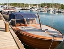 En träbåt som ligger vid en brygga med andra båtar.