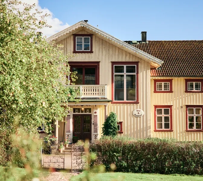 Ett gult hus med brunt tak och röda lister.