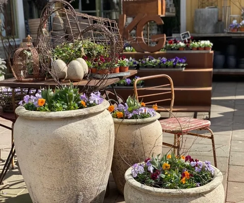 Blomster i krukor och dekorativa trädgårdsdetaljer på Kärrstegens Gård.