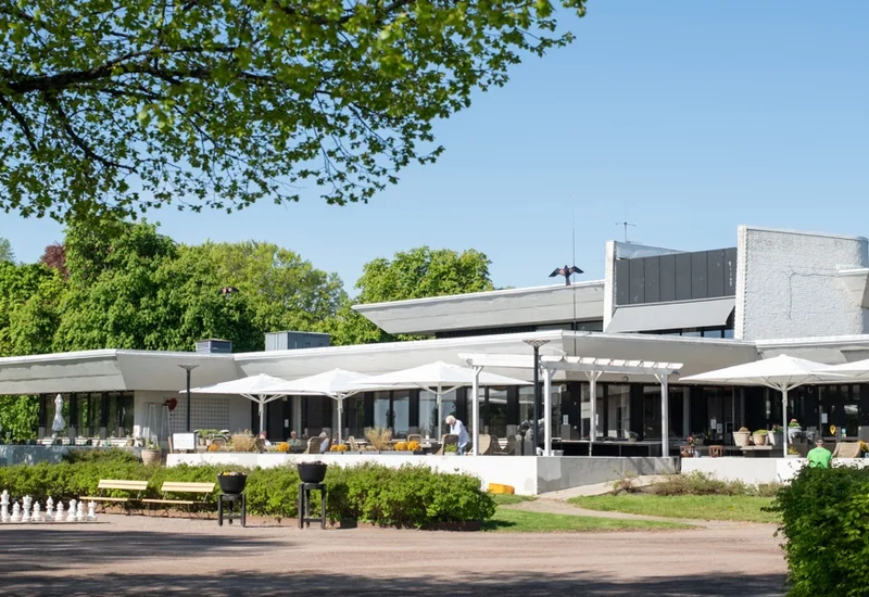 Ett hotell och deras uteservering, framför är en stor grusplan.