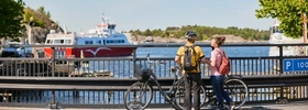 Två personer cyklar i en småstad.