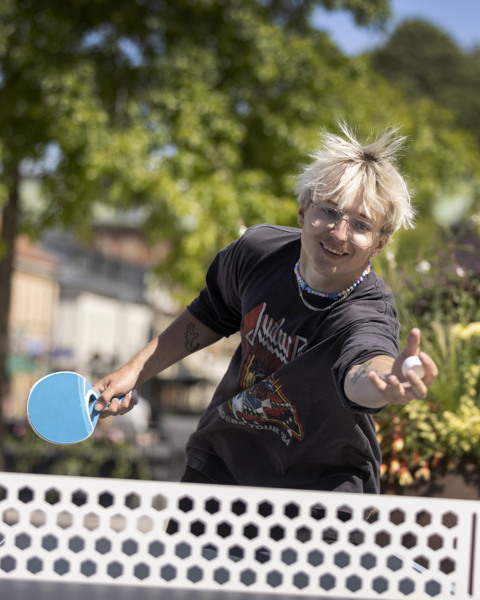 En kvinna spelar pingis i en park.
