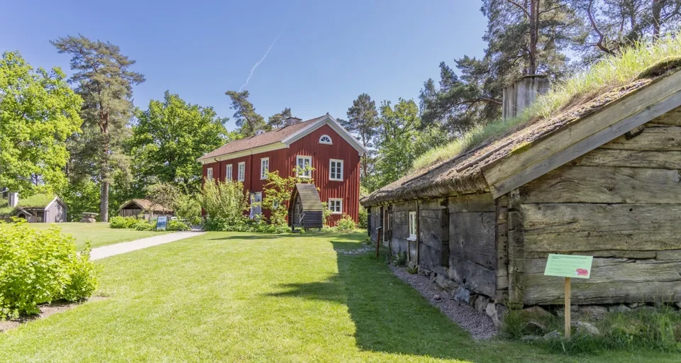 Ett rött hus med ett grönt tak och ett grästak.