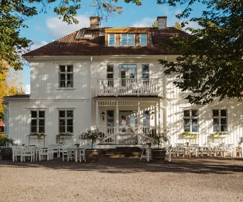 Ett stort vitt hus som sitter under ett träd.