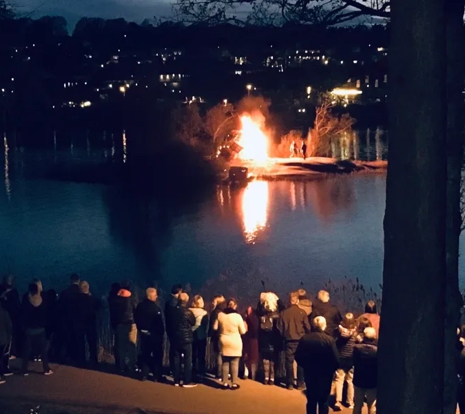 En grupp människor som står runt en sjö på natten.
