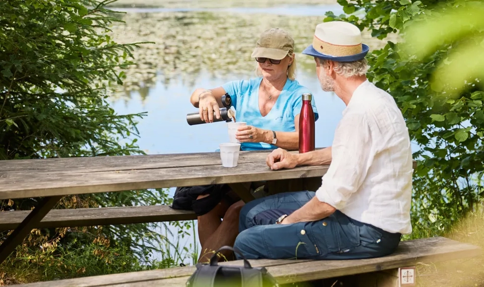 Två personer som vandrar på pilgrimsled genom skogen.