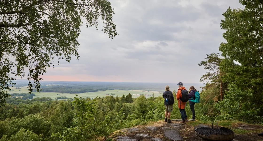 Människor står vid en utsiktsplats och tittar ut över landskap.