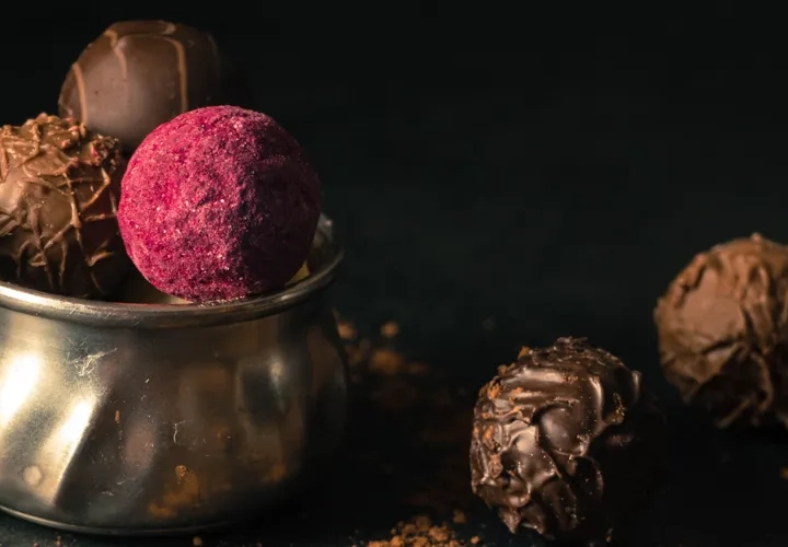 En metallkopp fylld med chokladbitar bredvid en sked.
