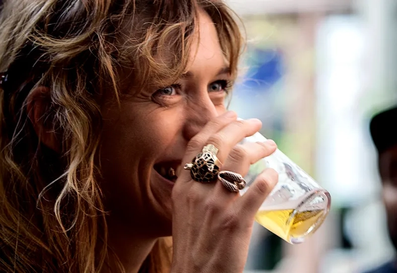 En kvinna som dricker ett glas öl medan hon står bredvid en man.