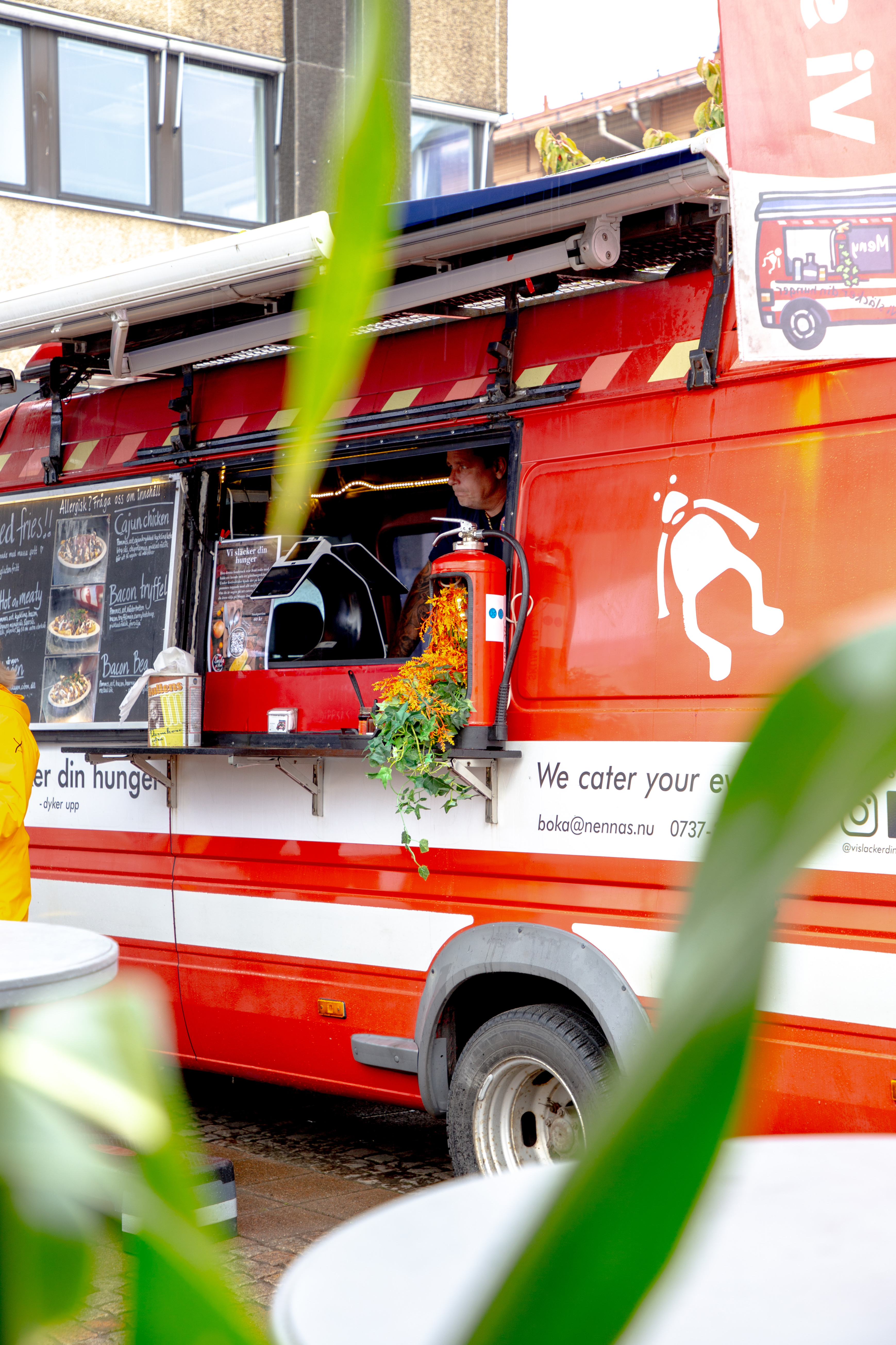 En röd och vit food truck parkerad framför en byggnad.