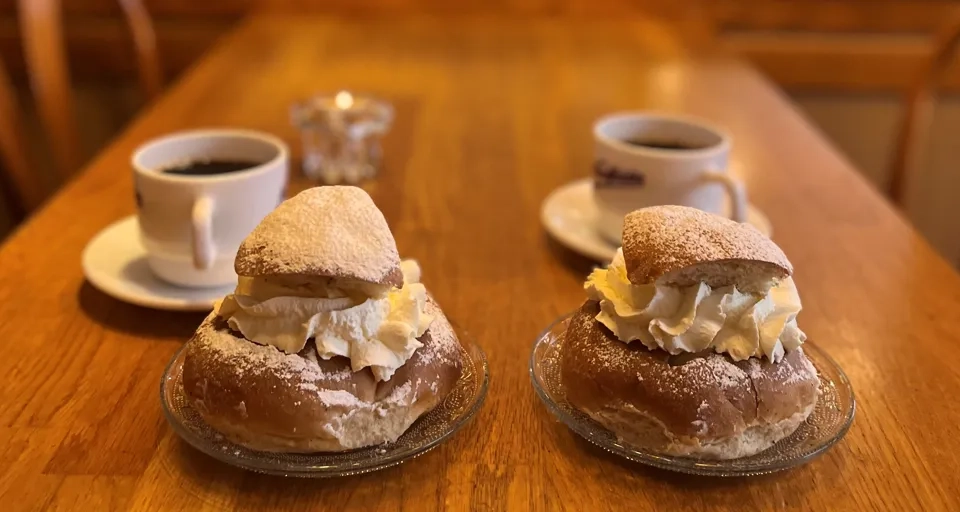 Ett bord med två semlor och två koppar kaffe.