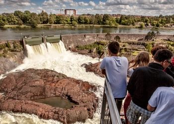 En grupp människor som står på en bro och tittar på ett vattenfall.