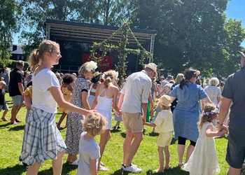 Människor som dansar runt en midsommarstång