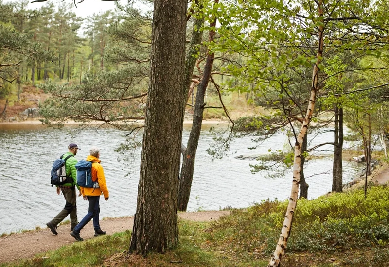 Några människor som går längs en stig intill en sjö vid Gotaleden.
