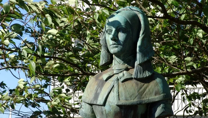 En staty av en kvinna framför ett träd.