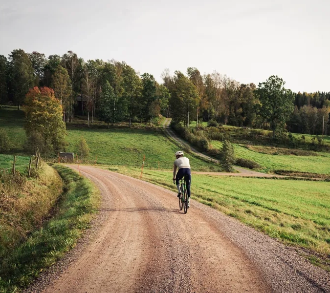 Cyklist på en grusväg i bruksmiljö.