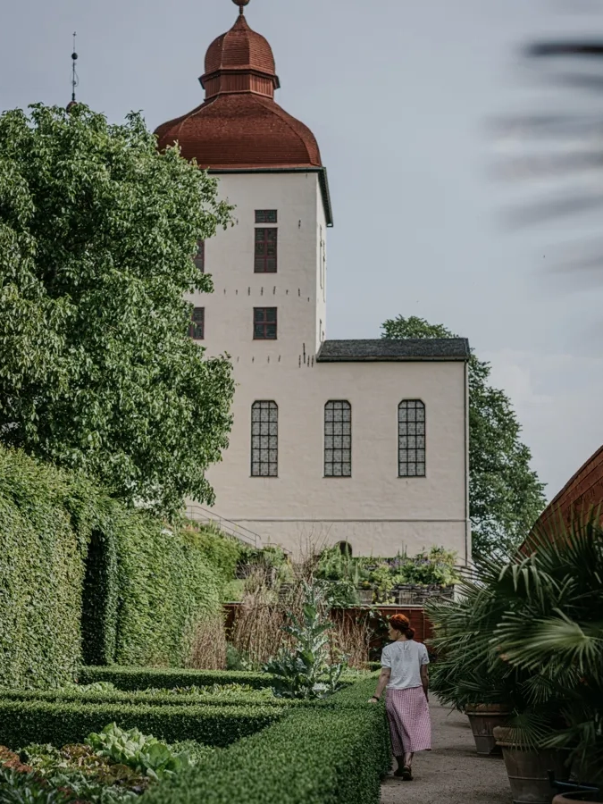 Kvinna strosar i Lilla Slotsträdgården vid Läckö Slott