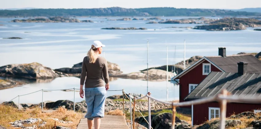 En kvinna som går längs en stig på Ursholmen mot havet.