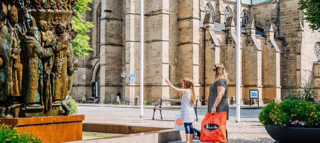 Två personer tittar på Krönikebrunnen vid Stortorget i Skara