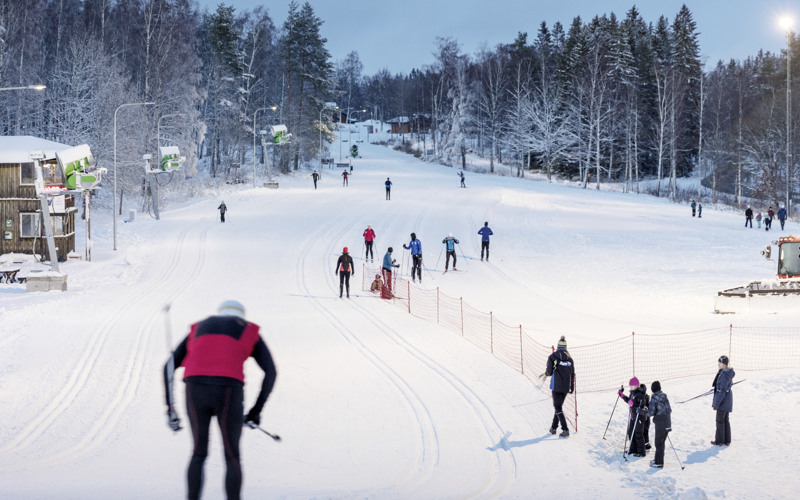 En grupp människor som åker längdskidor nedför en snötäckt sluttning.