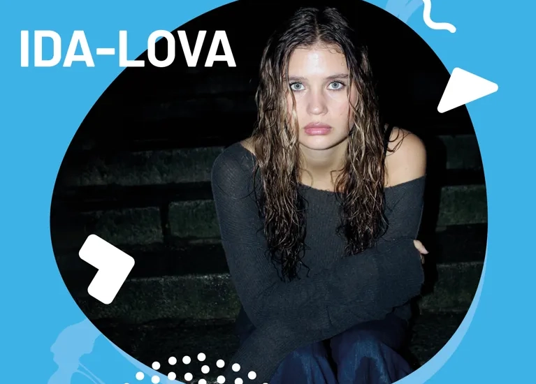 En kvinna sitter på en bänk med armarna i kors.