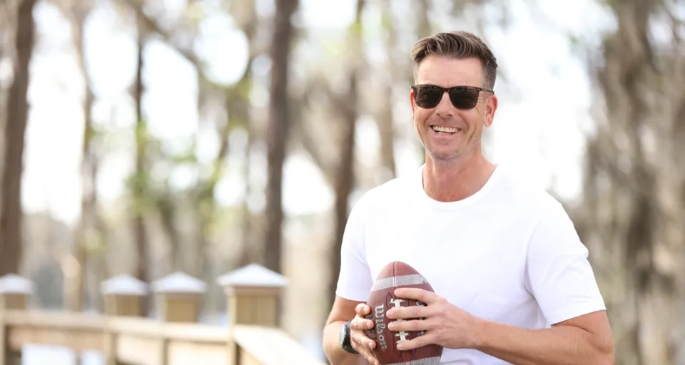 En man sitter på en bänk och håller i en fotboll.