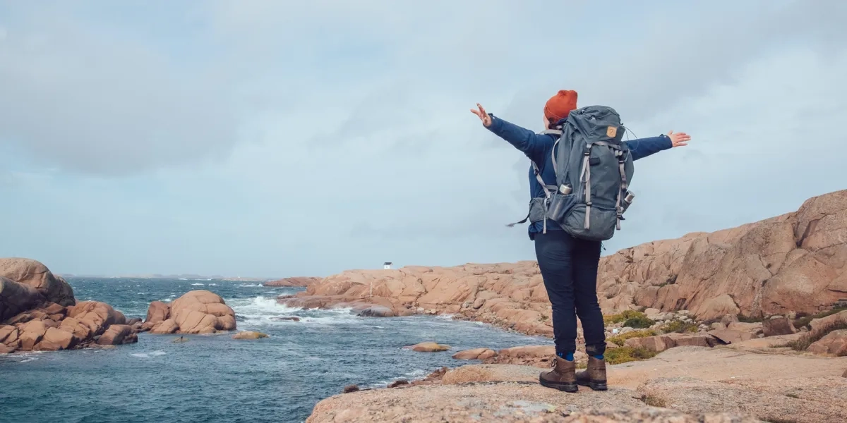 Eine Person, die oben auf einem Felsen am Meer steht.