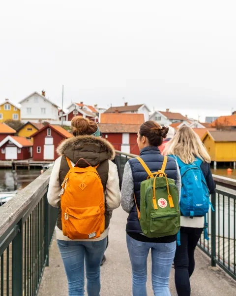 Tre personer går på en bro över ett vattendrag.