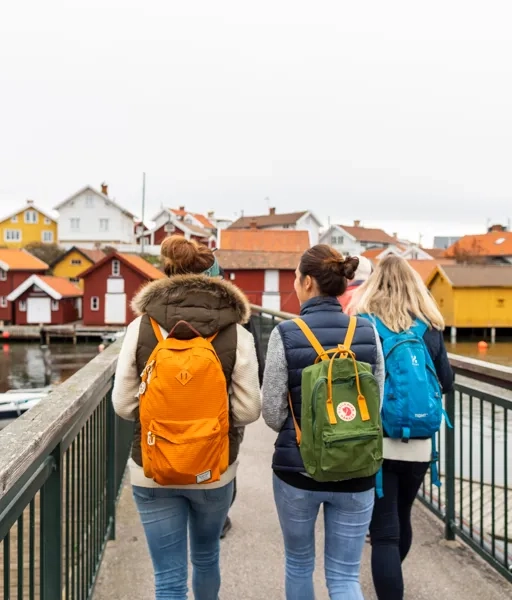 Tre personer går på en bro över ett vattendrag.