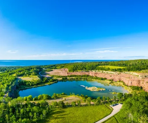 Det gamla kalkstenbrottet fyllt med klarblått vatten. Stenbrottet är omringad av grönvuxen natur.