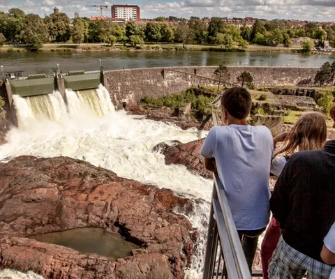 En grupp människor som står på en bro och tittar på ett vattenfall.
