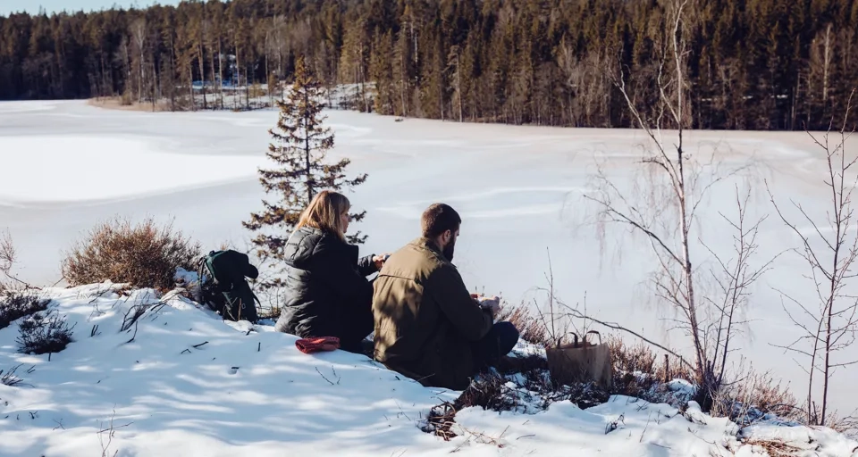 Vänner som vintervandrar i skogslandskap i Västsverige.