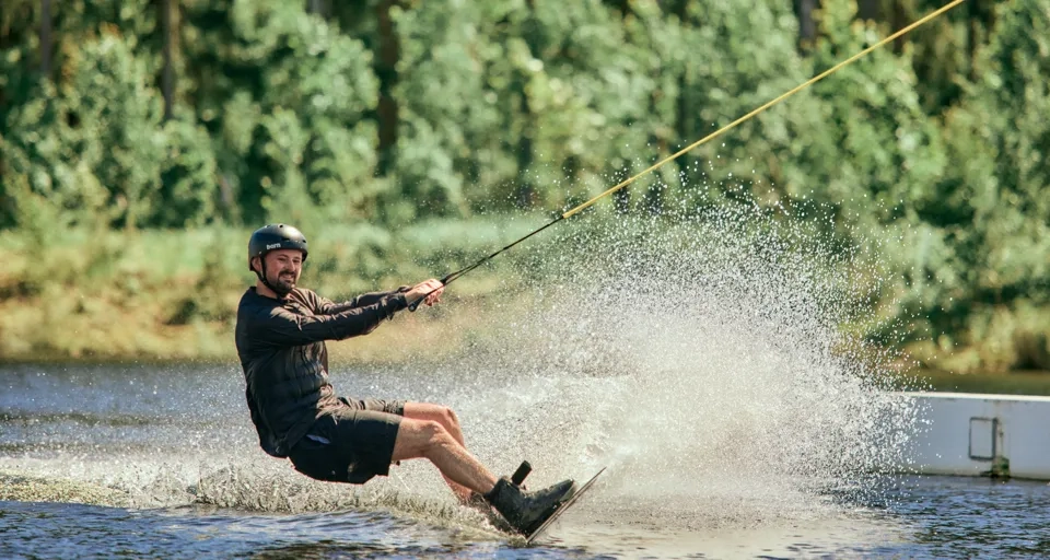 En man åker wakeboard medan han dras av en båt.