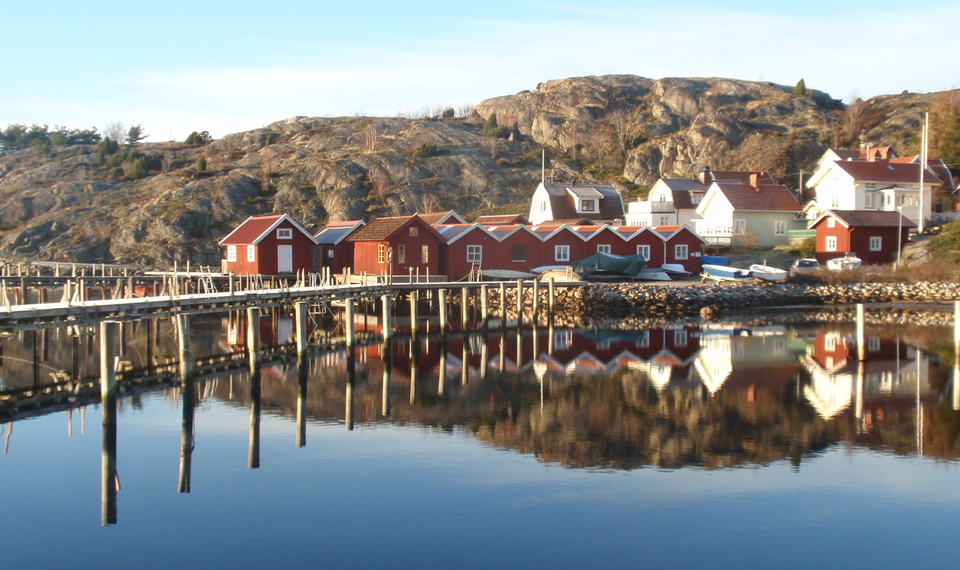 Stilla hav med bryggor, sjöbodar och kaptenshus. 