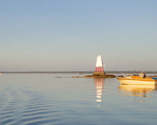 En fritidsbåt på Vänern. En liten fyr i bakgrunden.