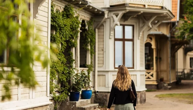 Eine Frau, die einen Feldweg vor einem Haus entlanggeht.