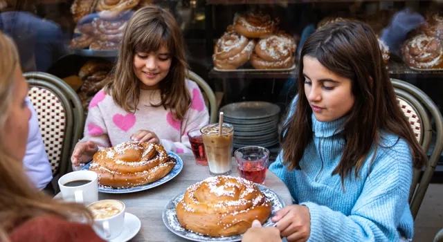 A group of girls sitting at a table with cinnamon buns.